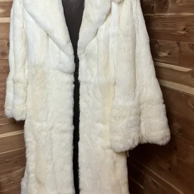 Sale Photo Thumbnail #146: Vintage full-length white fur coat featuring a brown lining with embroidered initials "CG" hanging in a cedar closet.