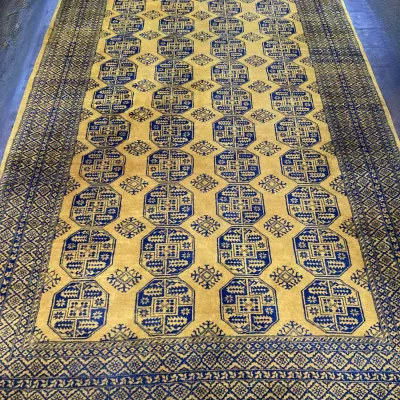 Sale Photo Thumbnail #50: Vintage golden yellow and navy blue Bukhara style area rug featuring repeating octagonal gul motifs and fringed ends.