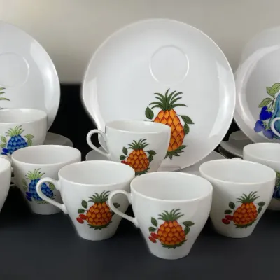 Sale Photo Thumbnail #229: Vintage white ceramic snack set featuring colorful pineapple and fruit motifs, including matching teacups and indented tray plates.