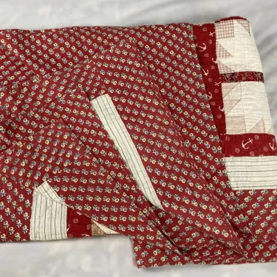 Sale Photo Thumbnail #172: Hand-stitched patchwork quilt featuring red floral backing, star-patterned blocks, and nautical anchor accents.