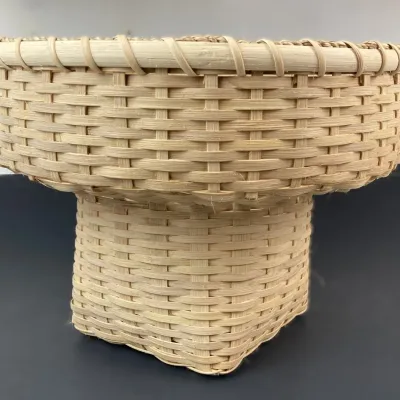 Sale Photo Thumbnail #224: Handwoven light reed pedestal basket, featuring a wide round rim atop a square woven base in excellent condition.