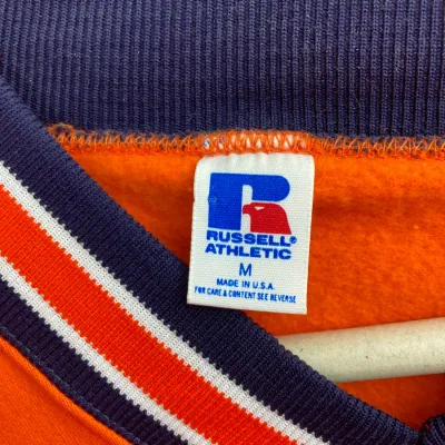 Sale Photo Thumbnail #159: Vintage Russell Athletic orange sweatshirt, size medium, featuring a red and blue eagle tag and striped knit trim.