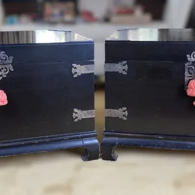 Sale Photo Thumbnail #81: Pair of Asian-style black lacquered wooden chests featuring ornate brass hardware and decorative pink tassels.