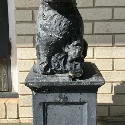 Sale Photo Thumbnail #216: Vintage Asian-style Foo dog garden statue mounted on a matching pedestal, featuring weathered dark grey paint with chipping surface wear.