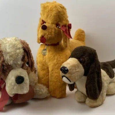 Sale Photo Thumbnail #138: Trio of vintage plush stuffed dog toys, including a Saint Bernard with a keg barrel, a yellow standing poodle with ear ribbons, and a basset hound.