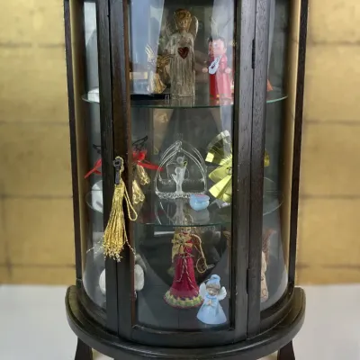 Sale Photo Thumbnail #176: Vintage dark wood curved tabletop curio cabinet filled with various angel figurines and ornaments, featuring glass shelves and a tassel key detail.