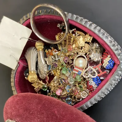 Sale Photo Thumbnail #238: Vintage heart-shaped velvet-lined jewelry box filled with assortment of costume jewelry, brooches, charms, and a silver-tone bangle.