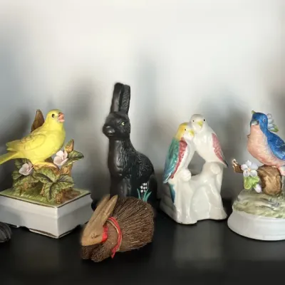 Sale Photo Thumbnail #97: Collection of decorative bird figurines and rabbit sculptures in ceramic and cast metal displayed on a shelf.