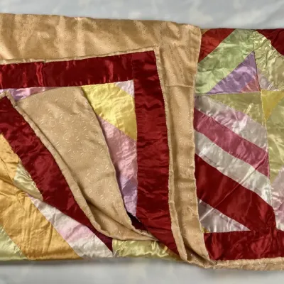 Sale Photo Thumbnail #104: Handmade vintage satin crazy quilt featuring colorful geometric star panels, a deep red border, and a patterned tan backing.