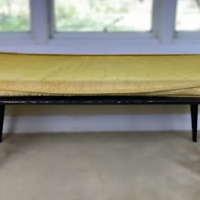 Sale Photo Thumbnail #82: Mid-century modern bench featuring tapered black legs and a removable mustard yellow cushion, showing light wear to the wooden base.
