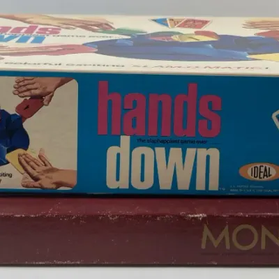 Sale Photo Thumbnail #183: Vintage Hands Down board game by Ideal stacked on top of a classic Parker Brothers Monopoly game box, showing shelf wear along the edges.