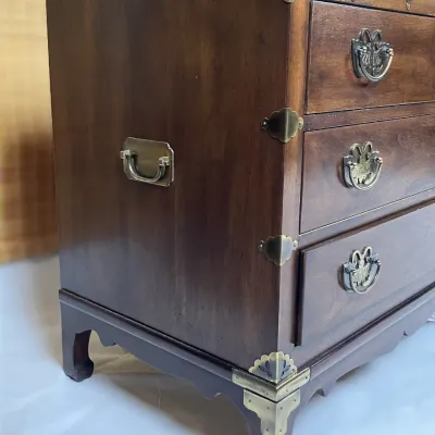 Sale Photo Thumbnail #59: Korean-style campaign chest featuring dark wood construction, brass corner hardware, ornate butterfly drawer pulls, and side carrying handles.