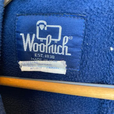 Sale Photo Thumbnail #163: Vintage Woolrich blue fleece jacket featuring an original sheep logo tag and wooden hanger.