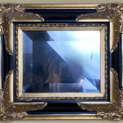 Sale Photo Thumbnail #171: Ornate wall mirror featuring a gilded and black painted frame with acanthus leaf corner details and a beveled glass panel.