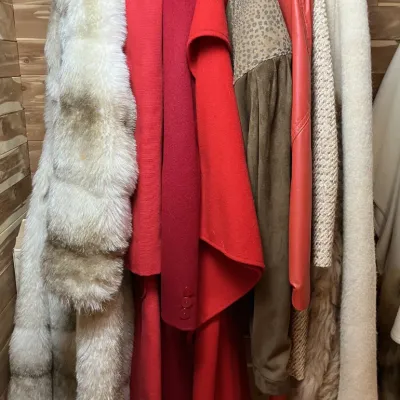 Sale Photo Thumbnail #147: Collection of vintage women's outerwear hanging in a closet, featuring a white fur coat, red wool coats, suede jacket, and shearling-trimmed coats.
