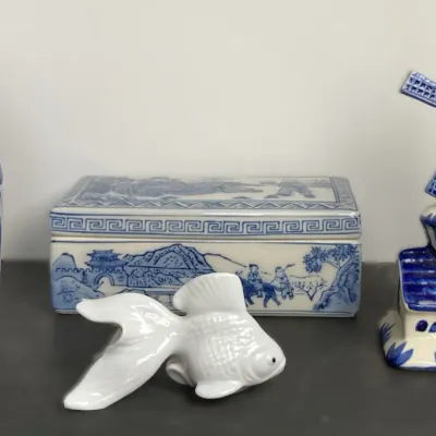 Sale Photo Thumbnail #89: Collection of blue and white ceramic decorative items, including a floral vase, trinket box, windmill figurine, and a small white goldfish sculpture.