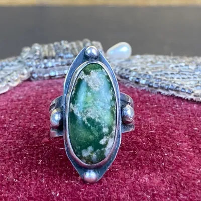 Sale Photo Thumbnail #239: Vintage Southwestern sterling silver ring featuring a large oval green turquoise cabochon with silver bead accents.