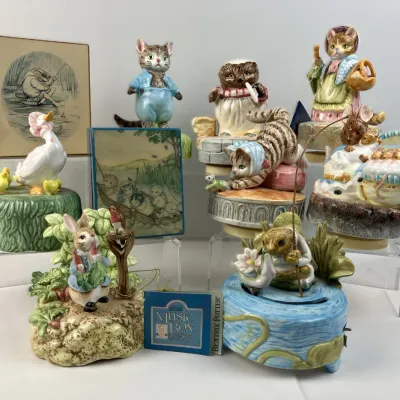 Sale Photo Thumbnail #197: Collection of Beatrix Potter vintage porcelain music boxes and ceramic figurines by Schmid, featuring characters like Jemima Puddle-Duck, Peter Rabbit, and Mrs. Tiggy-Winkle.
