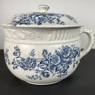 Sale Photo Thumbnail #95: Antique blue and white transferware ceramic chamber pot with lid and handle, featuring floral patterns and minor age-related discoloration.