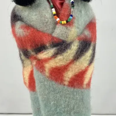 Sale Photo Thumbnail #194: Vintage Native American-style souvenir doll dressed in a patterned wool blanket, beaded necklace, and headband, displayed on a metal stand.
