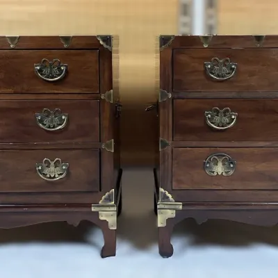 Sale Photo Thumbnail #58: Pair of Asian campaign-style wooden three-drawer nightstands featuring decorative brass hardware and corner mounts.