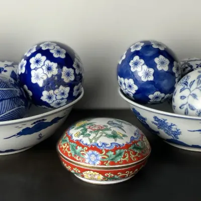 Sale Photo Thumbnail #96: Collection of decorative ceramic sphere balls in blue-and-white patterned porcelain, displayed inside two matching ceramic bowls alongside a polychrome floral trinket box.