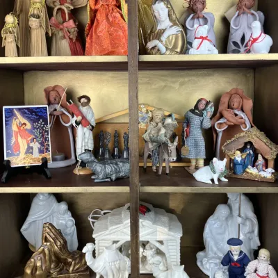 Sale Photo Thumbnail #213: Collection of nativity figures, angel figurines, and religious decor displayed across three wooden cabinet shelves.