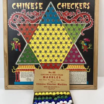 Sale Photo Thumbnail #186: Vintage framed Chinese Checkers game board featuring vibrant graphic art, complete with its original boxed set of 60 solid color marbles by Berry Pink Industries.