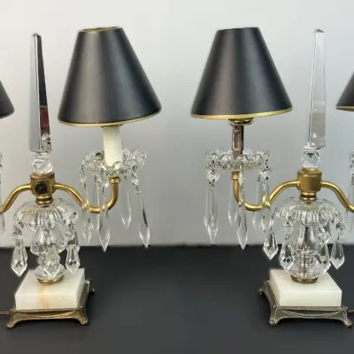 Sale Photo Thumbnail #30: Pair of vintage French-style two-light crystal candelabra table lamps featuring central obelisks, hanging prism drops, marble bases, and black shades.
