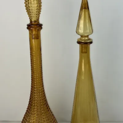 Sale Photo Thumbnail #32: Pair of vintage amber glass decanters featuring one with a diamond-point hobnail texture and one smooth ribbed, both with matching pointed stoppers.