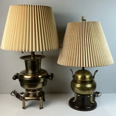 Sale Photo Thumbnail #73: Pair of vintage brass Asian-style table lamps featuring a samovar-form base and a tripod incense burner-form base, both topped with pleated beige fabric shades.