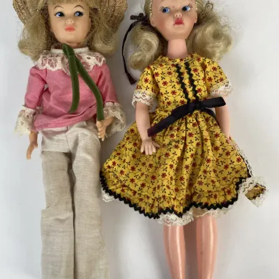 Sale Photo Thumbnail #191: Pair of vintage blonde fashion dolls from the 1960s or 1970s, featuring one in a straw hat and pants set and the other in a yellow floral dress.