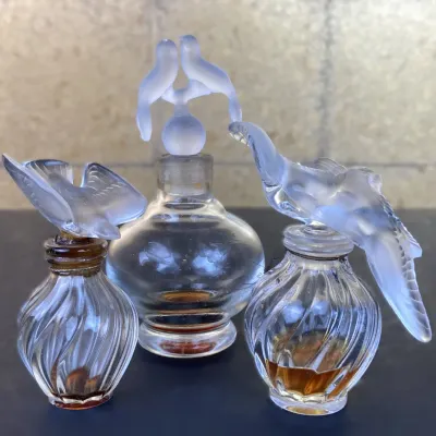 Sale Photo Thumbnail #170: Trio of vintage Nina Ricci 'L'Air du Temps' glass perfume bottles with frosted dove stoppers in various sizes.