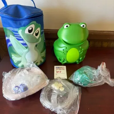 Pediatric frog-themed nebulizer compressor system with matching blue carrying case, tubing, and mask accessories.