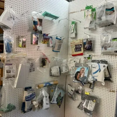 A pegboard display wall featuring various packaged medical supplies, supports, CPAP masks, and health accessories.