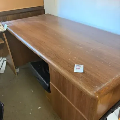 Large wooden executive office desk showing surface scratches and wear from use, late 20th century.