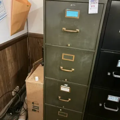 Vintage olive green steel four-drawer filing cabinet by Steelcase with brass hardware, showing moderate surface wear.