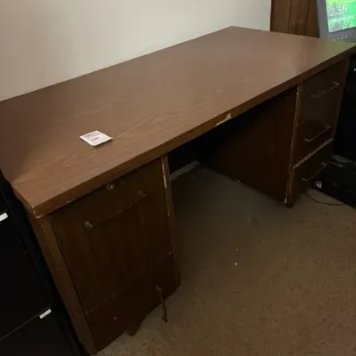 Vintage wood-laminate executive office desk featuring double pedestals with drawers, showing edge wear and slight laminate peeling on one...
