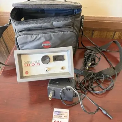 Dura-Neb 1000 portable aerosol compressor nebulizer with power adapter and a grey PARI zippered carrying bag.