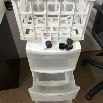 White plastic three-drawer rolling storage cart with detached caster wheels, paired with a white plastic milk crate style basket.