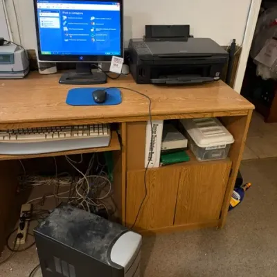 Vintage desktop computer setup including a dusty PC tower, LCD monitor displaying Windows XP, keyboard, mouse, printer, and an...