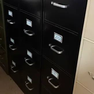 Set of black four-drawer metal filing cabinets with silver handles and alphabetical label holders.