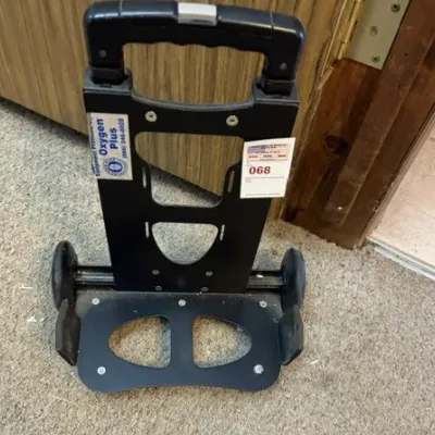 Black plastic and metal portable luggage or oxygen tank cart with telescoping handle and wheels.