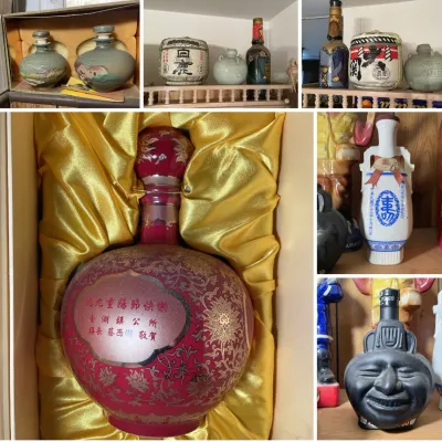Sale Photo Thumbnail #213: Collection of decorative vintage Asian liquor decanters and sake vessels, including a large red and gold commemorated bottle in a lined box.