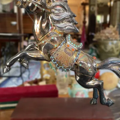 Sale Photo Thumbnail #22: Ornate silver-plated rearing horse figurine, featuring filigree work and turquoise-style stone embellishments, mounted on a wooden base.