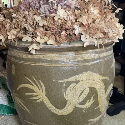 Sale Photo Thumbnail #37: Large glazed ceramic fish bowl planter featuring relief dragon motifs, filled with dried floral arrangements.