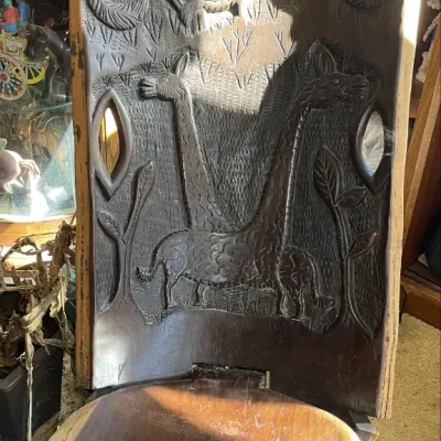 Sale Photo Thumbnail #35: Hand-carved African wooden chair featuring relief carvings of giraffes and birds on the tall backrest.