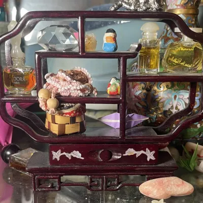 Sale Photo Thumbnail #187: Miniature Asian-style wooden curio display shelf filled with small trinkets, including vintage perfume bottles, crystals, and handmade crafts.