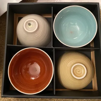 Sale Photo Thumbnail #87: Boxed set of four Miya Japan ceramic rice bowls featuring textured spiral exteriors and contrasting glazed interiors in light grey, turquoise, reddish-brown, and yellow.