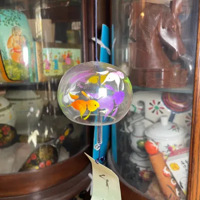 Sale Photo Thumbnail #126: Japanese hand-painted glass wind chime (fūrin) featuring colorful goldfish motifs, hanging by a blue cord with a paper wind catcher.